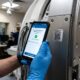 healthcare-mri-asset-scan Technician scanning the QR asset label on an MRI scanner with a mobile app before a maintenance inspection